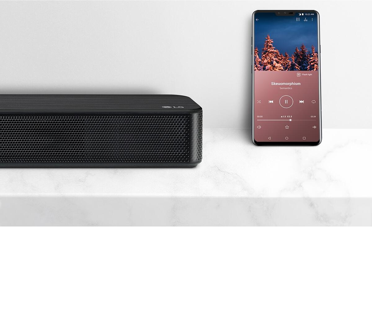 Close-up right side of LG Soundbar next to smartphone. Two devices are on the white shelf.