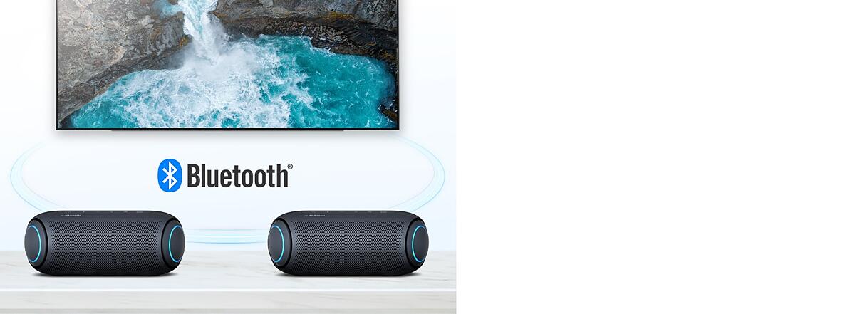 On a table, two LG XBOOM Go with sky blue lighting are in front of a TV showing a waterfall.