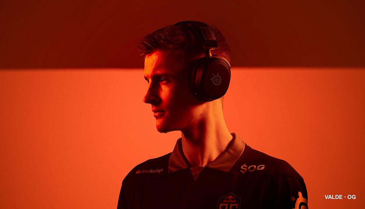 OG player Valde stands against an orange background wearing the Arctis Prime headset.